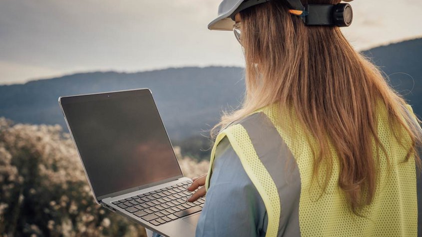 Eine Ingenieurin auf der Baustelle schaut auf ihren Laptop